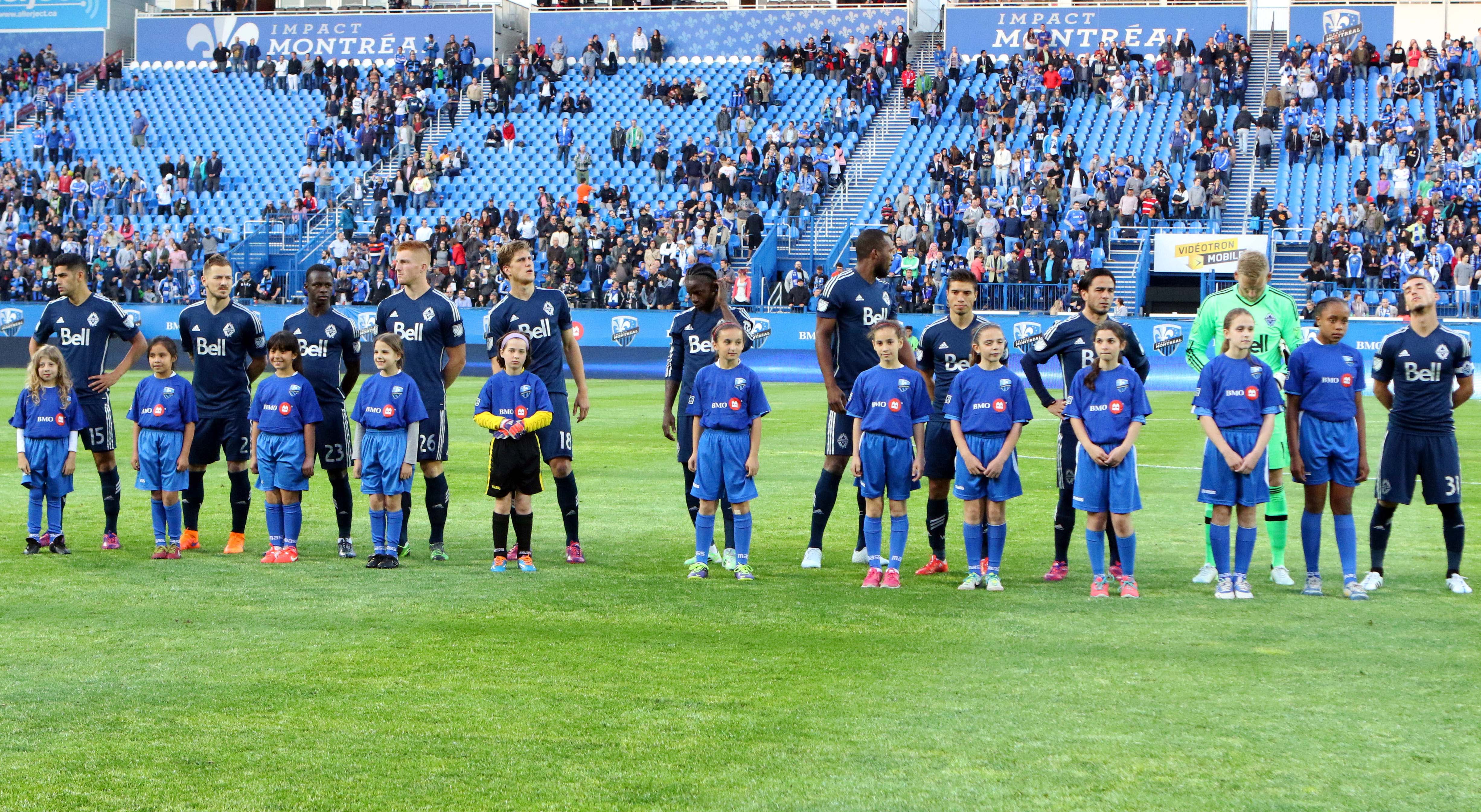 Jun 3, 2015; Montreal, Quebec, CAN; Vancouver FC players and youngsters stand up during the national anthems before the first half against Montreal Impact at Stade Saputo. Mandatory Credit: Jean-Yves Ahern-USA TODAY Sports